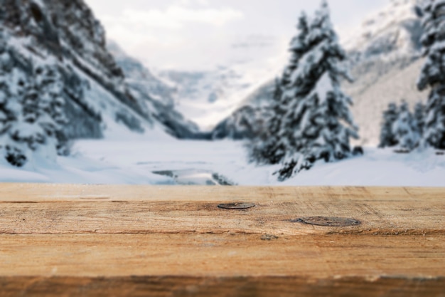 Holzbrett und Berge mit Bäumen im Schnee