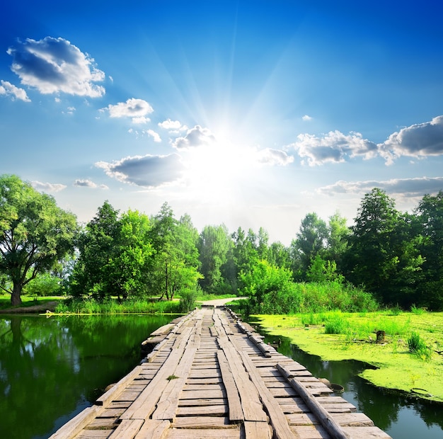 Holzbrücke an einem stillen Fluss an einem sonnigen Tag