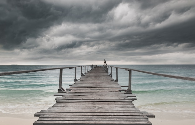 Holzbrücke und das Meer mit dunklem Regen bewölktes schwaches Licht.