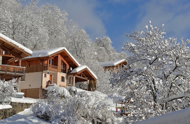 Holzchalets im Alpendorf mit Schnee im weißen Baumberg bedeckt?