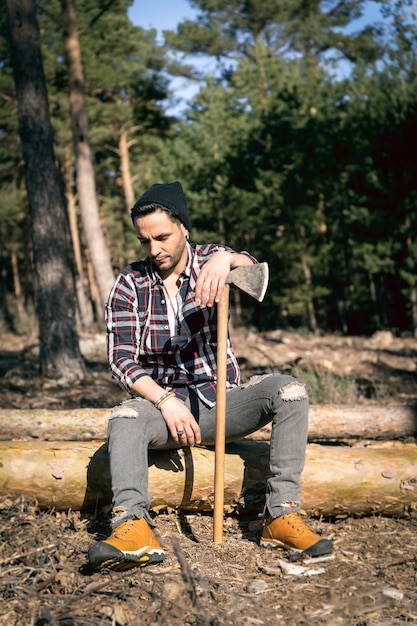 Holzfäller Mann sitzt auf Holzklotz an seine Axt gelehnt