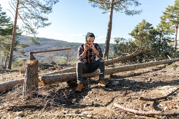 Holzfäller Mann sitzt auf Holzklotz neben seiner Axt und spricht auf dem Handy