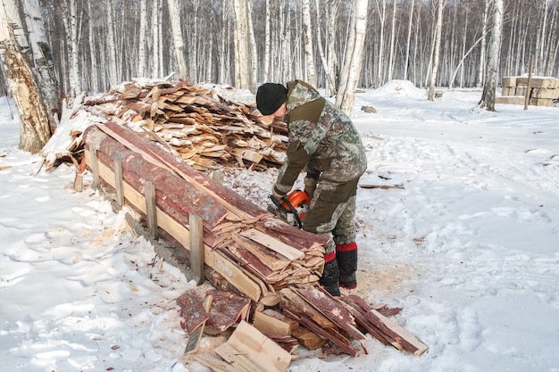 Holzfäller sägt im winter einen baum im wald, russland für brennholz