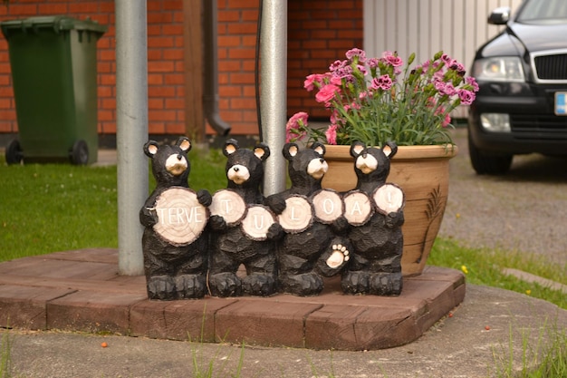 Holzfiguren von Bären sitzen auf einer Betonplatte mit der Aufschrift „Willkommen“ in finnischer Sprache