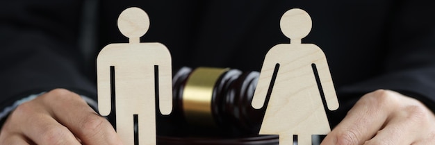 Holzfiguren von Mann und Frau in den Händen des Richters vor dem Hintergrund des Richterhammerkonzepts