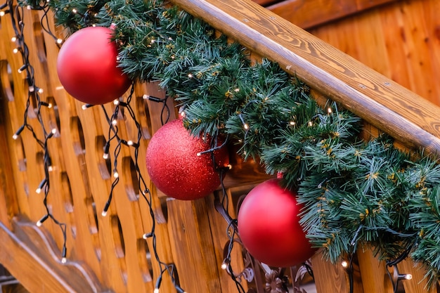 Holzgebäude aus künstlichem Tannenbaum mit Girlande und vielen roten Weihnachtskugeln
