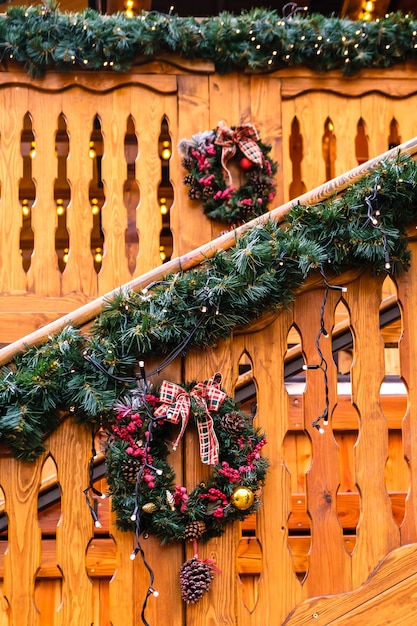 Holzgebäude aus künstlichem Tannenbaum mit Lichtgirlande und vielen roten Weihnachtsglocken