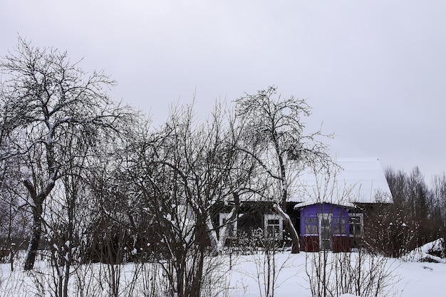 Holzgebäude und schneebedeckter Garten auf dem Land