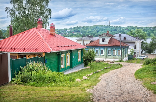 Holzhäuser in der Stadt Plyos, der Wolga und Häuser des Dorfes auf der anderen Seite in der Ferne an einem Sommertag