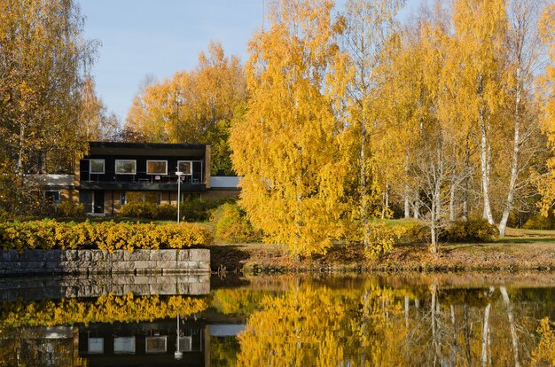 Holzhaus am Ufer unter den Herbstbäumen