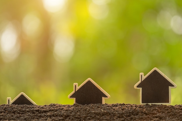 Holzhaus, das im Boden auf grünem Naturunschärfehintergrund wächst. Home Business aufwachsen Konzept