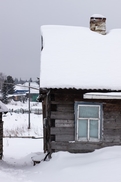 Holzhaus im Winter im Schnee. Ein Haus mit Kamin und Ofen.