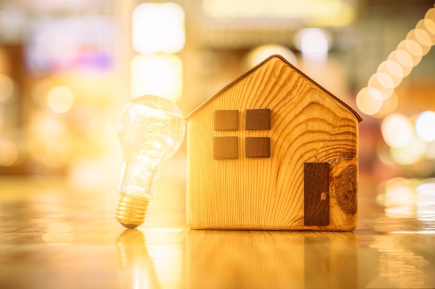 Holzhaus mit Glühbirne auf dem Tisch ein Symbol für den Bau