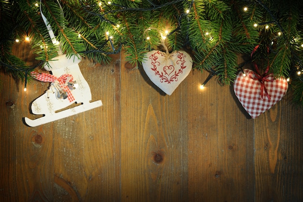 Foto holzhintergrund mit tannenzweigen, weihnachtsverzierung und lichtern