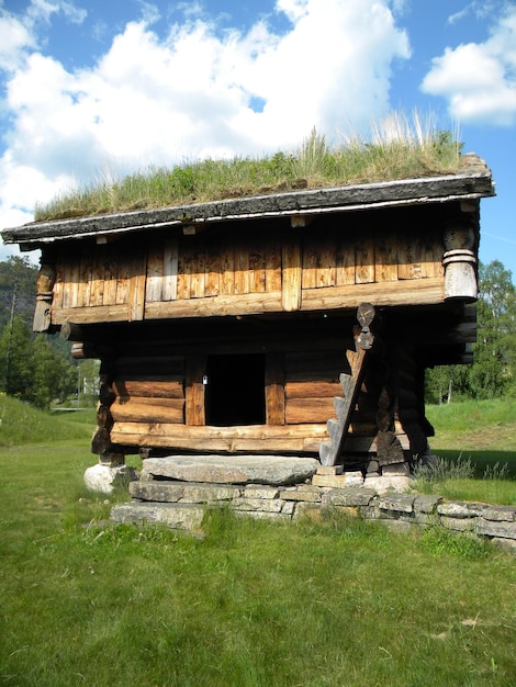 Foto holzhütte auf einem grasigen feld gegen einen bewölkten himmel