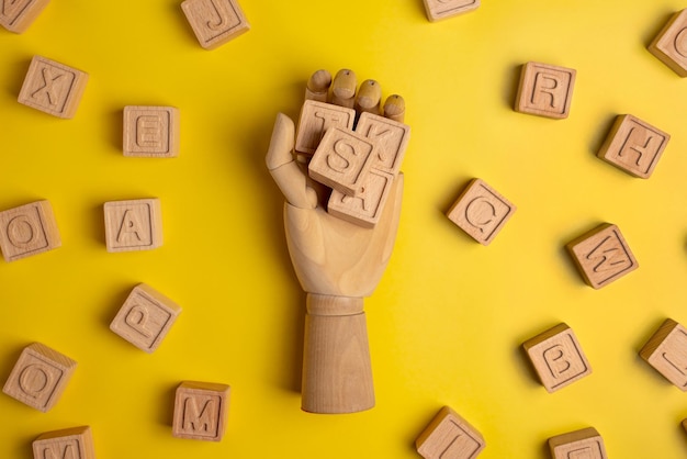 Holzjunge mit Buchstaben für Wörter in Holzhand auf gelbem Hintergrund Geschäfts- und Studienkonzept