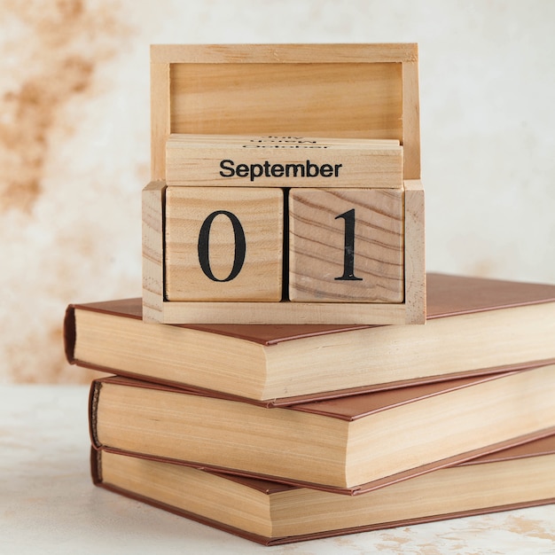 Holzkalender 1. September auf einem Stapel Bücher. Konzept für den Wissenstag, Beginn des Schuljahres.