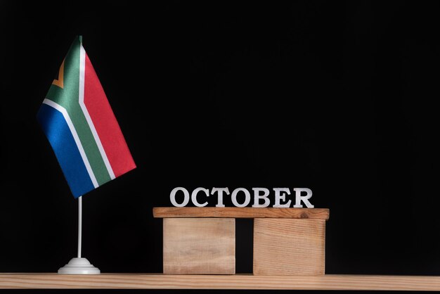 Holzkalender Oktober mit RSA-Flagge auf schwarzem Hintergrund Daten von Südafrika im Oktober