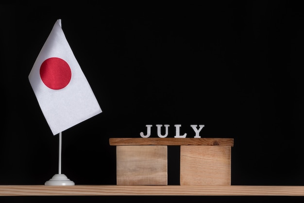 Holzkalender von Juli mit Japan-Flagge auf schwarzem Hintergrund.