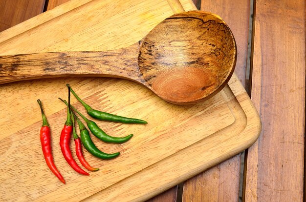 Holzkelle mit rotem und grünem Chili auf Holzbrett