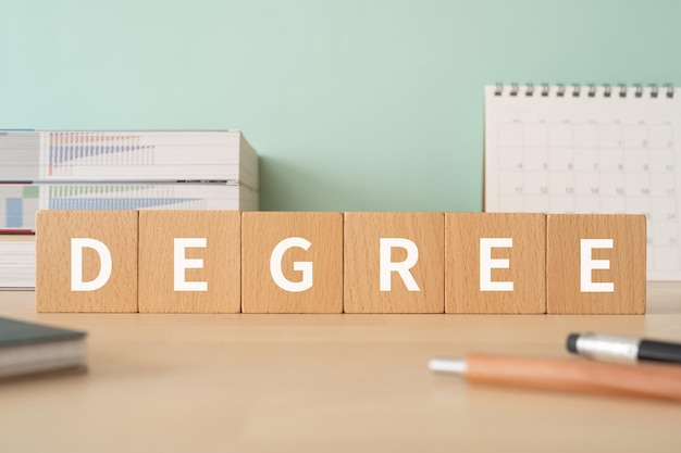 Foto holzklötze mit degree-konzepttext, stiften, notizbüchern und büchern.