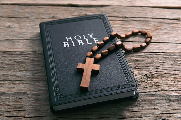 Holzkreuz mit der Heiligen Bibel auf dem Tisch