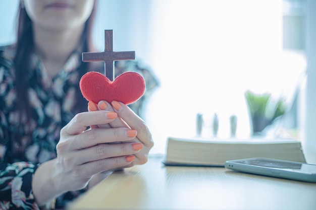 Holzkreuz und rotes Herz in weiblicher Hand mit Liebes- und Religionskonzept