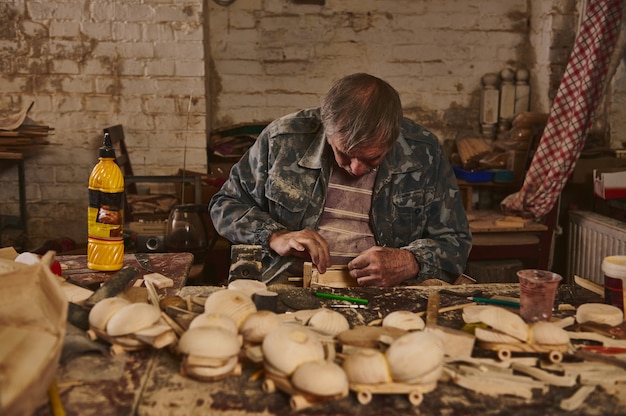 Holzkünstler, Handwerker, Tischler in einer Werkstatt zur Herstellung von handgefertigtem Holzspielzeug. Sicheres ökologisches Spielzeug für Kinder