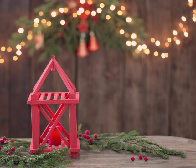 Holzlaterne mit Kerzen und Weihnachtszweigen auf Holzwand