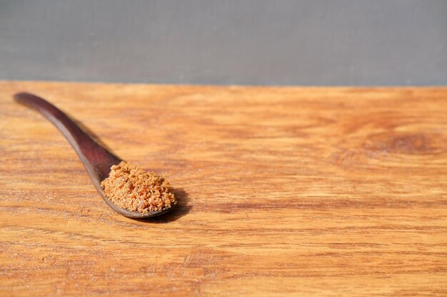 Holzlöffel mit braunem, natürlichem Muscovado-Zucker liegt auf Holztisch