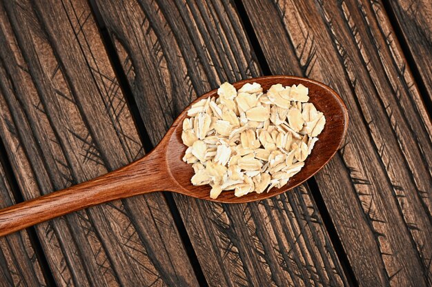 Holzlöffel mit Haferflocken auf einem Holzbrett