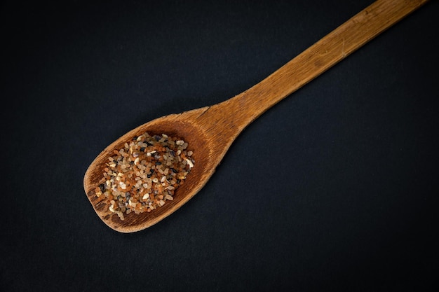 Holzlöffel mit Salz und Gewürzen auf dunklem Hintergrund