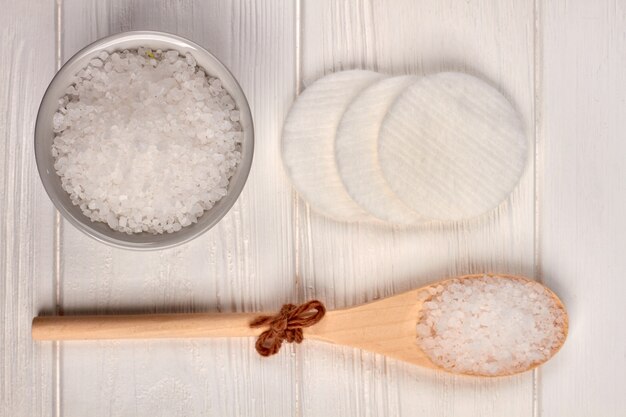 Holzlöffel mit Salz und Wattepads auf weißem Schreibtisch