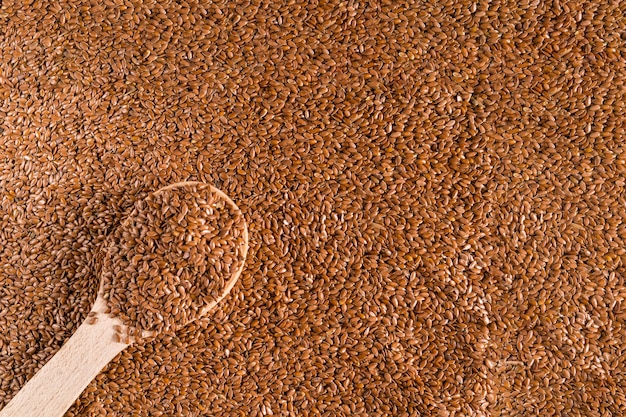 Holzlöffel über braunem Leinsamenhintergrund, flach liegen.