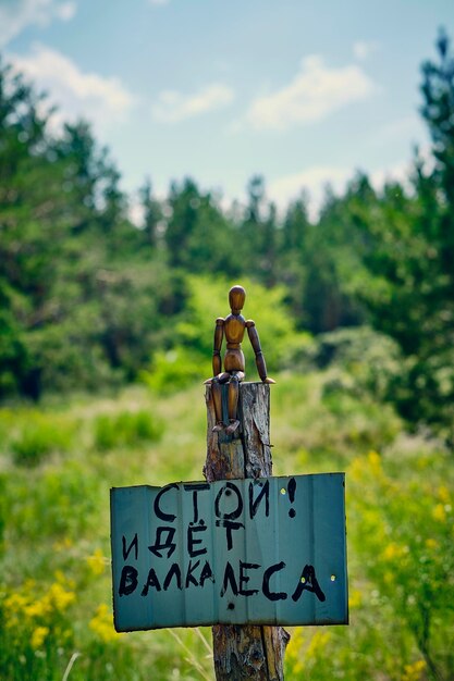 Holzmannequin sitzt auf einem Stumpf mit einem Schild, das mit der Aufschrift "Stop Logging" an dem Stumpf befestigt ist