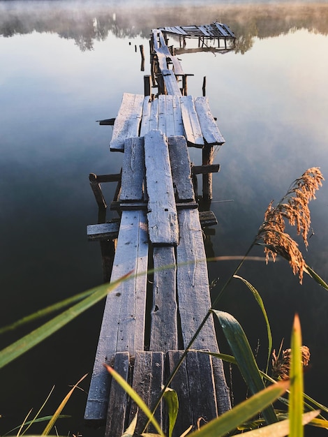 Holzmauerwerk am Ufer des Sees. Nebeliger Morgen. Ein fauler Pier auf einem ruhigen Teich.