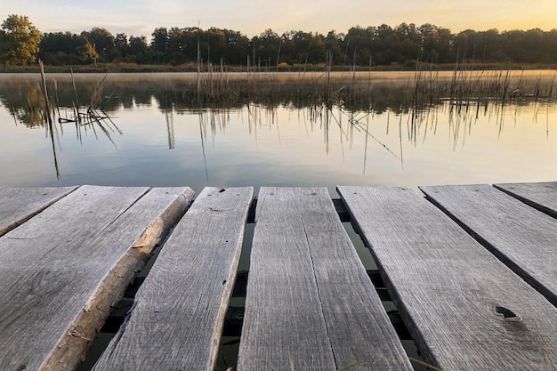 Holzmauerwerk am Ufer des Sees. Nebeliger Morgen. Ein fauler Pier auf einem ruhigen Teich.