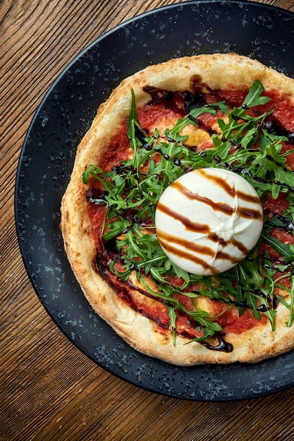 Holzofenpizza mit Burrata, Rucola, roter Sauce und Balsamico. Pizzette eine Art italienische Pizza