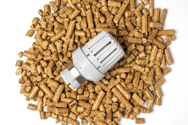 Holzpellets mit Thermostat Thermostatventilkopf isoliert auf weißem Hintergrund Erneuerbare Heizquelle Biokraftstoff Ökologischer Kraftstoff aus Biomasse Die Alternative Energiequelle Gaskrise