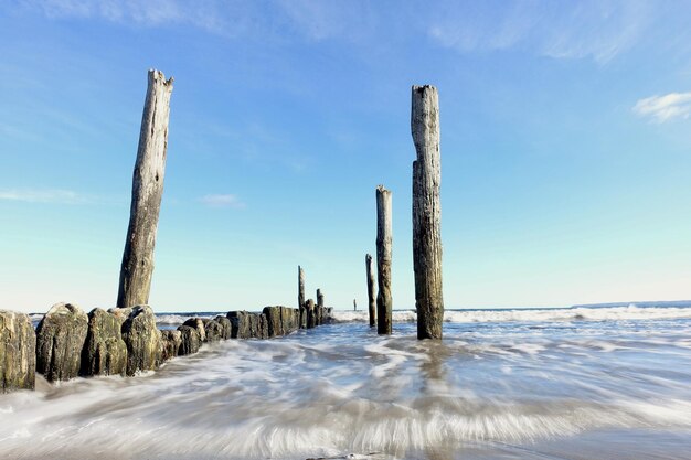 Foto holzpfähle auf dem meer gegen den blauen himmel