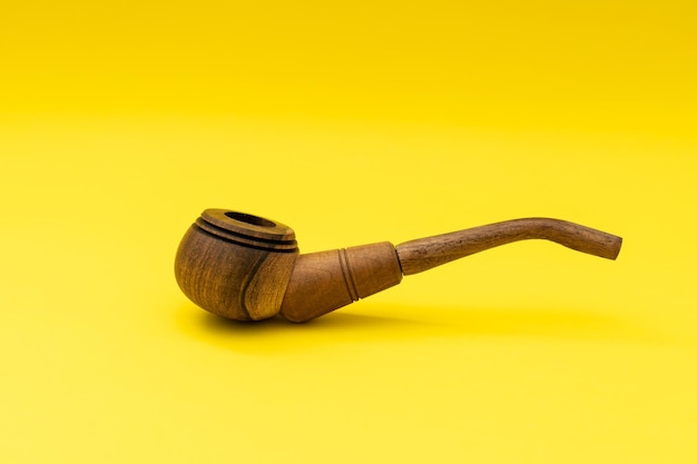 Holzpfeife mit Tabak auf gelbem Hintergrund Rauchen schadet