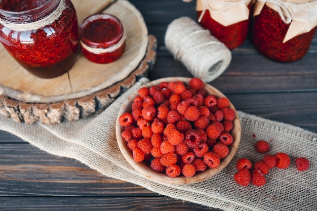 Holzplatte mit Himbeeren auf einem Hintergrund von Himbeermarmelade