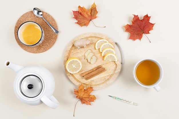 Holzplatte mit Zitronenscheiben, Ingwer und Zimtstangen In der Nähe der Schüssel Honig Teekanne eine Tasse Tee