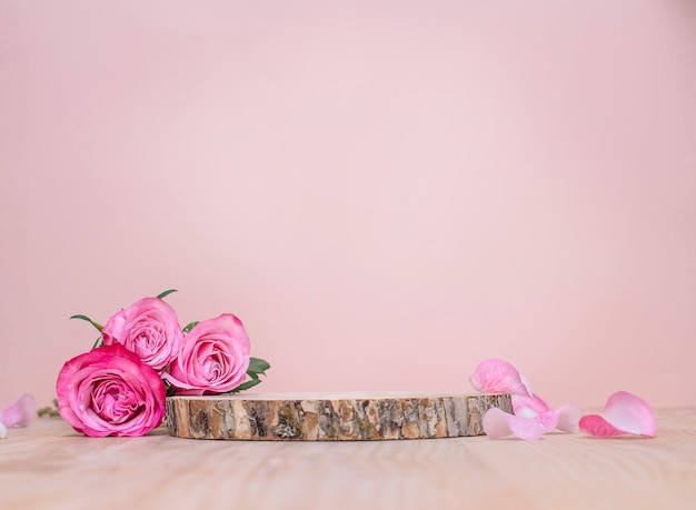 Holzpodium oder Produktbühne mit rosa Rosen auf pastellfarbenem Hintergrund
