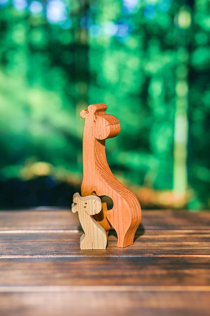 Holzpuzzle in Form einer Familie handgefertigter Giraffen auf dem Hintergrund des Waldes