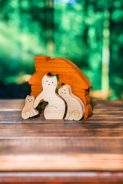 Holzpuzzle in Form einer Katzenfamilie in einem handgefertigten Haus auf dem Hintergrund des Waldes