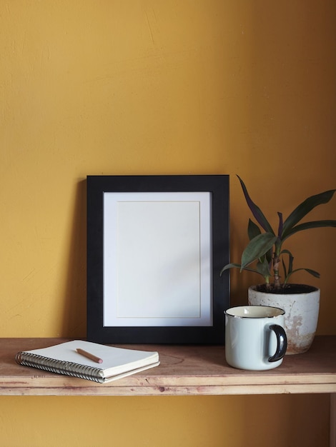 Holzrahmenmodell. Komposition mit einem Blumentopf, einem Notizbuch. Vor dem Hintergrund einer gelben Wand