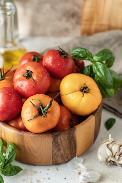 Holzschale mit frischen bunten Tomaten Knoblauch Basilikum Pfeffer und Olivenöl