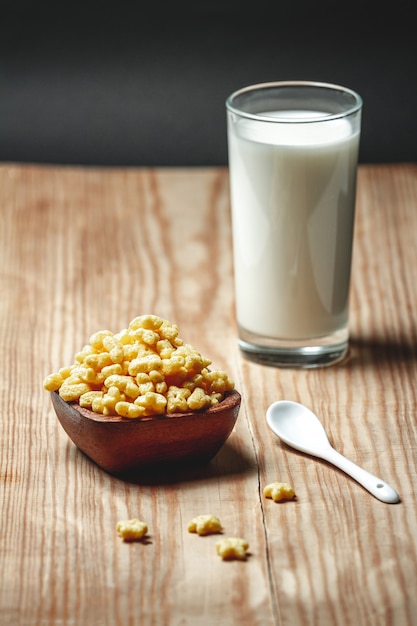 Holzschale mit schnellem Frühstücksflocken und einem Glas Milch