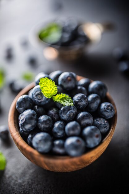 Holzschale voller frischer Blaubeeren mit Kräutern.